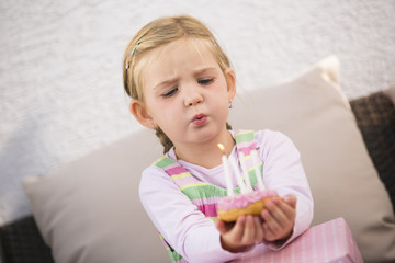 Junges Mädchen pustet auf Geburtstagkuchen Kerzen aus