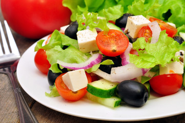 Greek salad and fork on a wooden table