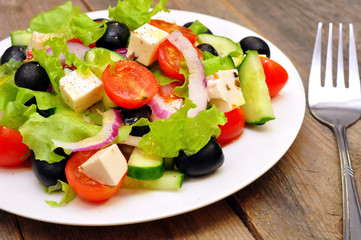 Greek salad and fork on a wooden table