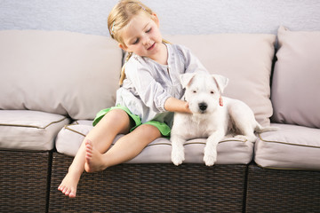Junges Mädchen streichelt ihren Hund auf Sofa sitzend