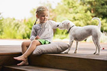 Junges Mädchen sitzt draußen auf Holztreppe mit ihrem Hund