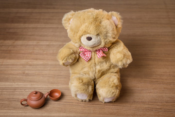 Toy teddy bear and tea kettle and cup