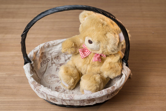 toy teddy bear in basket isolated on wooden desk
