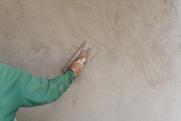 Worker wearing green shirts are using plastering gaskets to plaster the walls with copy space in construction work or house.