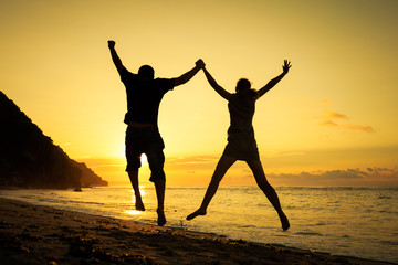 Happy family jumping on the beach at the dawn time