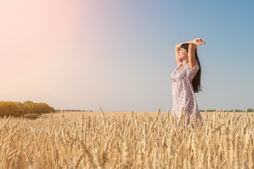 beautiful young woman in the wheat field at sunset