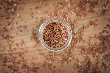 Brown rice in glass on wooden background