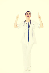 Beautiful young woman doctor pointing up.
