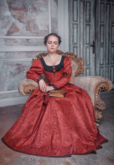 Beautiful woman in medieval dress on the armchair