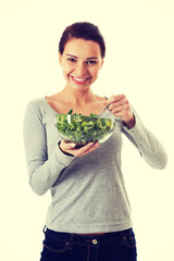 Young casual woman eating lamb's lettuce.