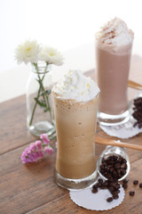 two Ice coffee with flower and coffee beans on a wood table