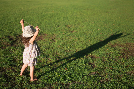 a girl standing on the grass looking at his shadow