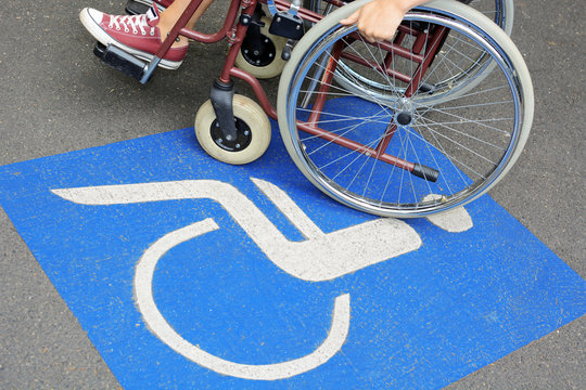 Frau mit Rollstuhl auf Behinderten-Parkplatz