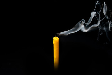 extinguished candle yellow with smoke, isolated over black