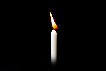 Burning white candle on black background