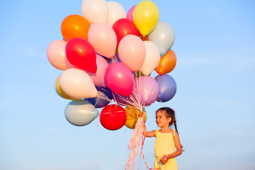 Fototapeta na wymiar Happy little girl child kid with balloons on sky background