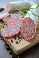 Salami sliced on cutting board with herbs