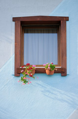 wooden window with flowers in blue wall