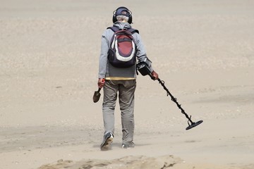 Mann mit Metalldetektor am Strand