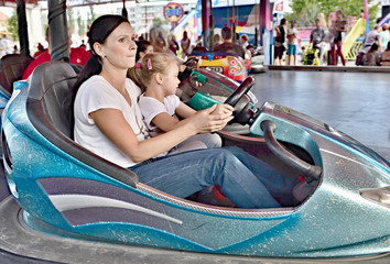 Mother and little daughter having fun rinding on carousel