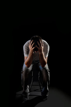 man sitting alone suffering emotional pain, grief, depression