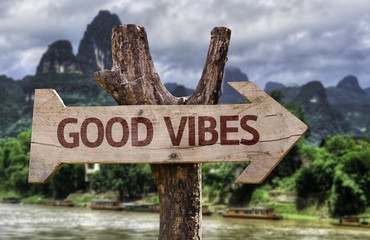 Good Vibes wooden sign with a forest background