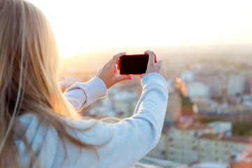 Beautiful blonde girl taking pictures of the city. - obrazy, fototapety, plakaty