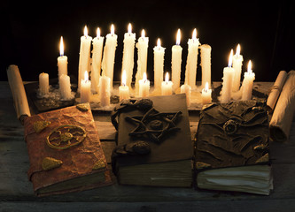 Three magic books with candles