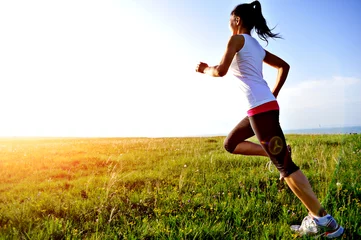 Afwasbaar Fotobehang Joggen Runner atleet loopt op zonsondergang gras aan zee