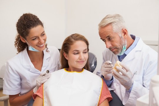 Dentist and assistant smiling with patient in chair