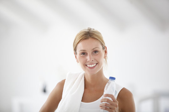 Fitness girl holding bottle of water after exercising