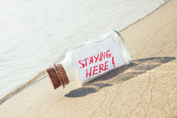 Creative summer vacation concept. Bottle with message on beach