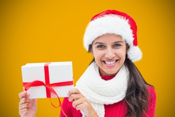 Composite image of festive brunette holding gift