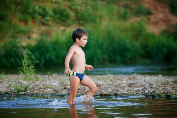 Fototapeta premium Boy walking on the water along the shore