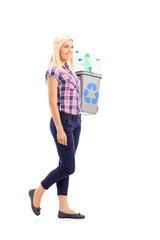 Profile shot of a woman carrying a recycle bin