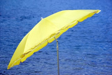 Gelber Sonnenschirm am blauen Meer