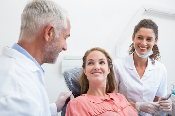 Fototapeta premium Dentist talking with patient while nurse prepares the tools