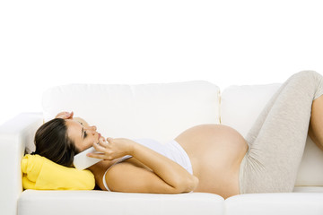 Pregnant woman with tablet lying on sofa