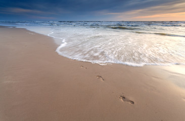 foot prints on sand beach at sunset