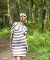 Fototapeta premium Girl walks on the wood in a dress