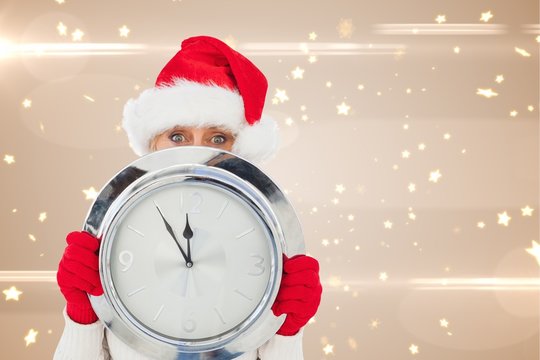 Composite image of festive woman holding clock