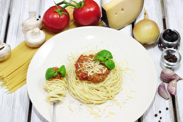 Spaghetti with parmesan and basil on white wood