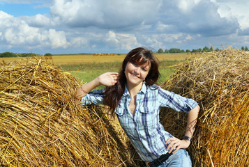 Yoing woman in haystacks on fields