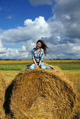 Naklejka na ściany i meble Yoing woman in haystacks on fields