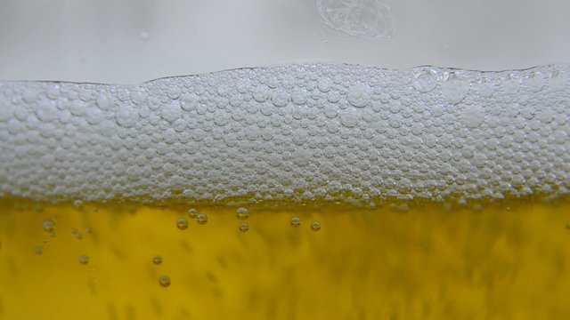 A pint glass is slowly filled with refreshing beer