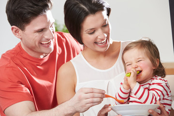 Parents Feeding Baby Daughter From Bowl
