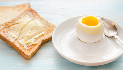 Boiled egg with crispy toasts on the wooden table