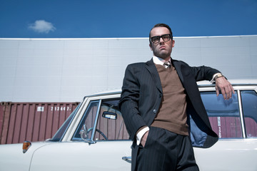 Retro 60s fashion business man wearing grey suit and glasses sta