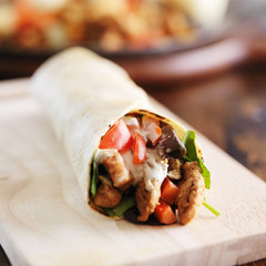chicken wrap in tortilla with sauce and mesclun mix