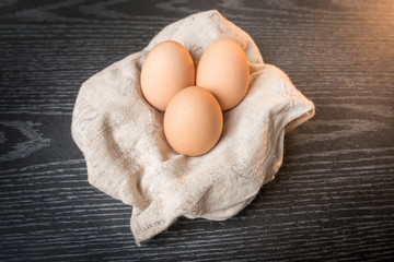 Chicken brown eggs in sackcloth on wooden background